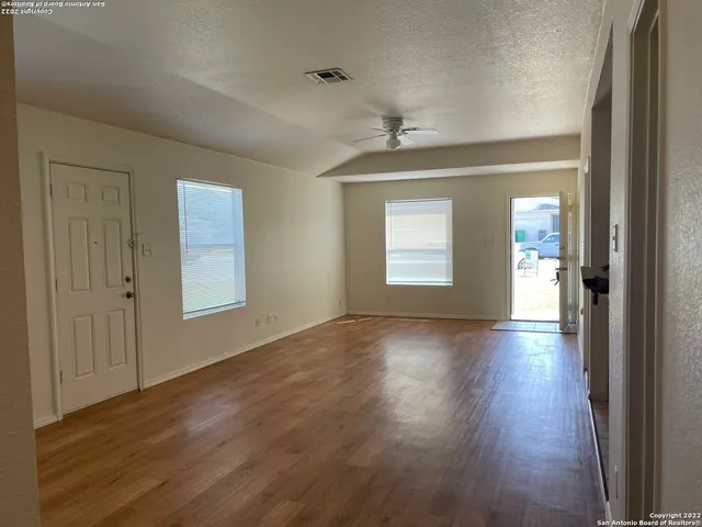 a view of an empty room with wooden floor and a window