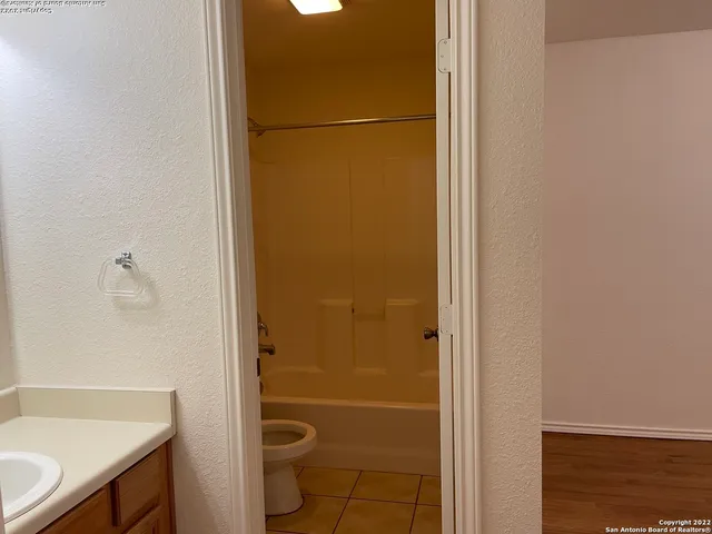 a bathroom with a granite countertop sink a toilet a mirror and shower