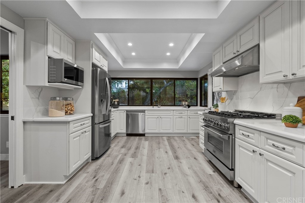 23524 Highland Glen Drive Newhall, CA 91321 - Photo 12 of 53 a kitchen with stainless steel appliances a stove top oven a sink a refrigerator white cabinets and wooden floor