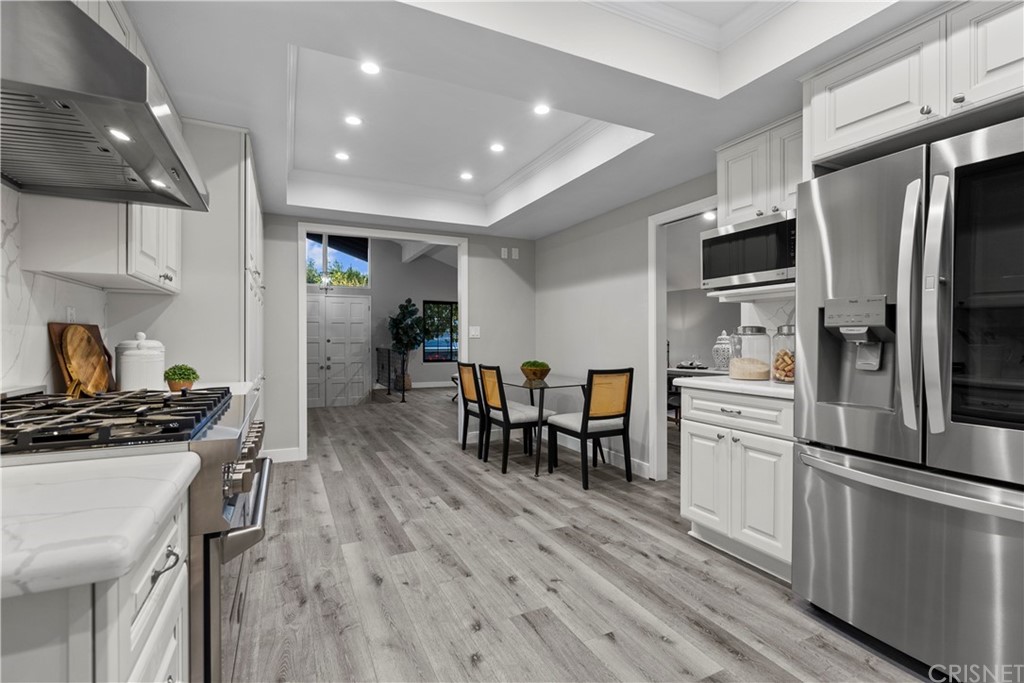 23524 Highland Glen Drive Newhall, CA 91321 - Photo 15 of 53 a kitchen with a refrigerator a stove and a dining table with wooden floor
