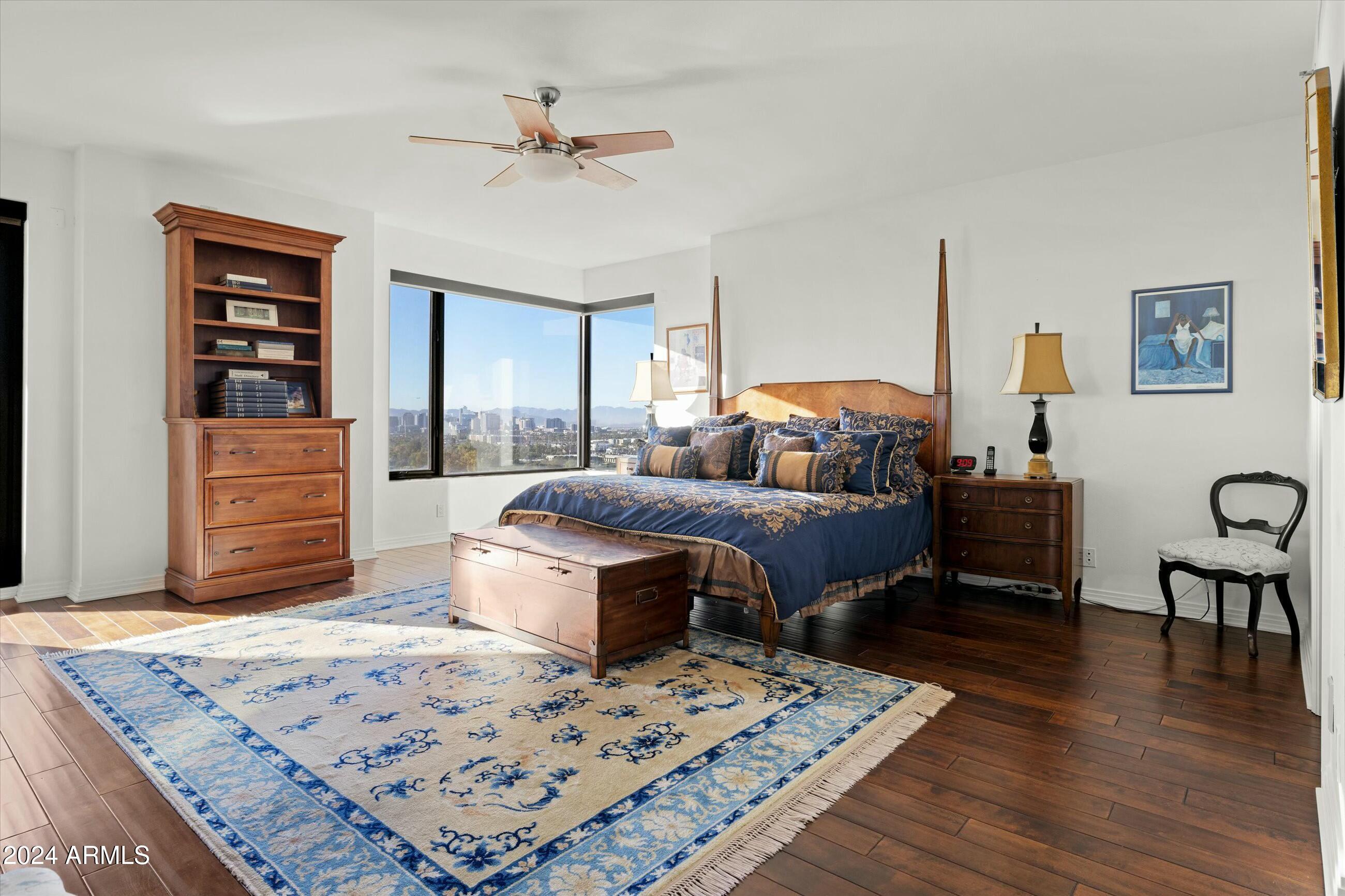 1040 East Osborn Road, Unit 1201 Phoenix, AZ 85014 - Photo 12 of 28 a bedroom with a bed a dresser and wooden floor