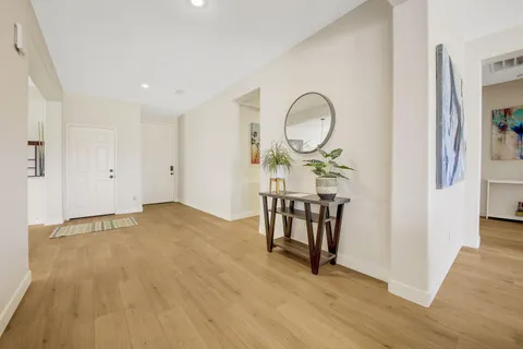 an empty room with wooden floor mirror and windows