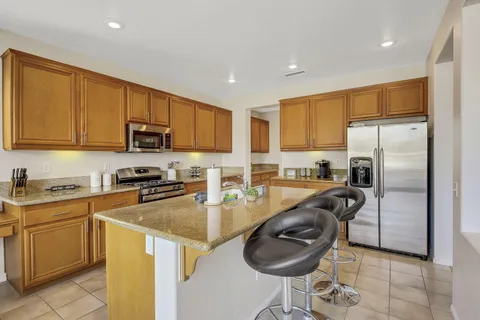 a kitchen with kitchen island granite countertop a stove a sink a refrigerator a window and cabinets