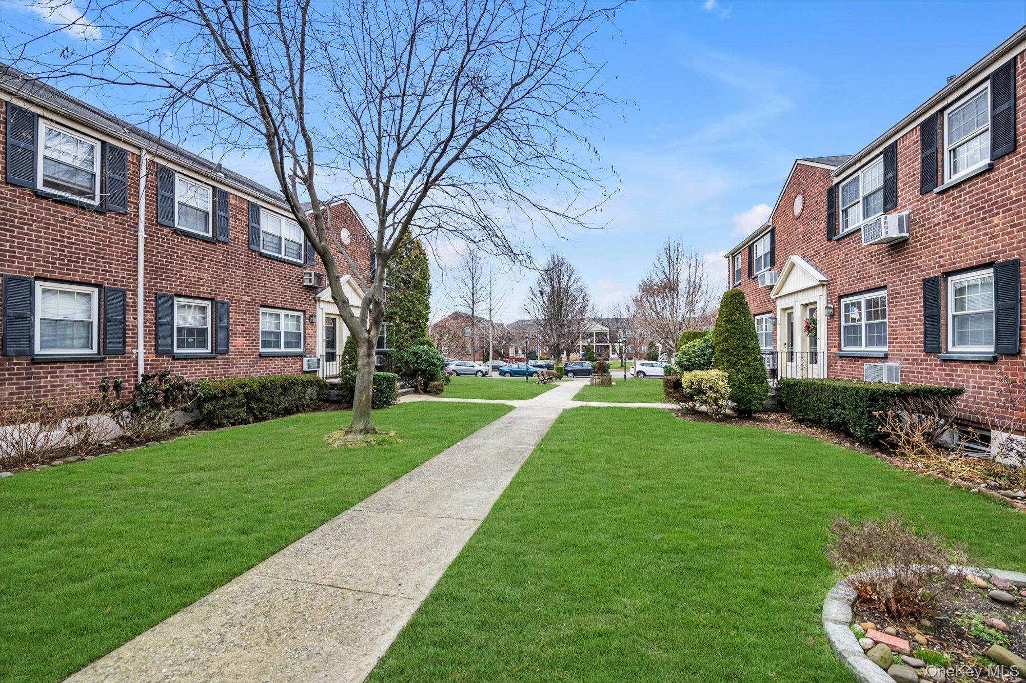 69-18 Bell Boulevard, Unit B Queens, NY 11364 - Photo 9 of 9 a view of a brick building next to a big yard and large trees