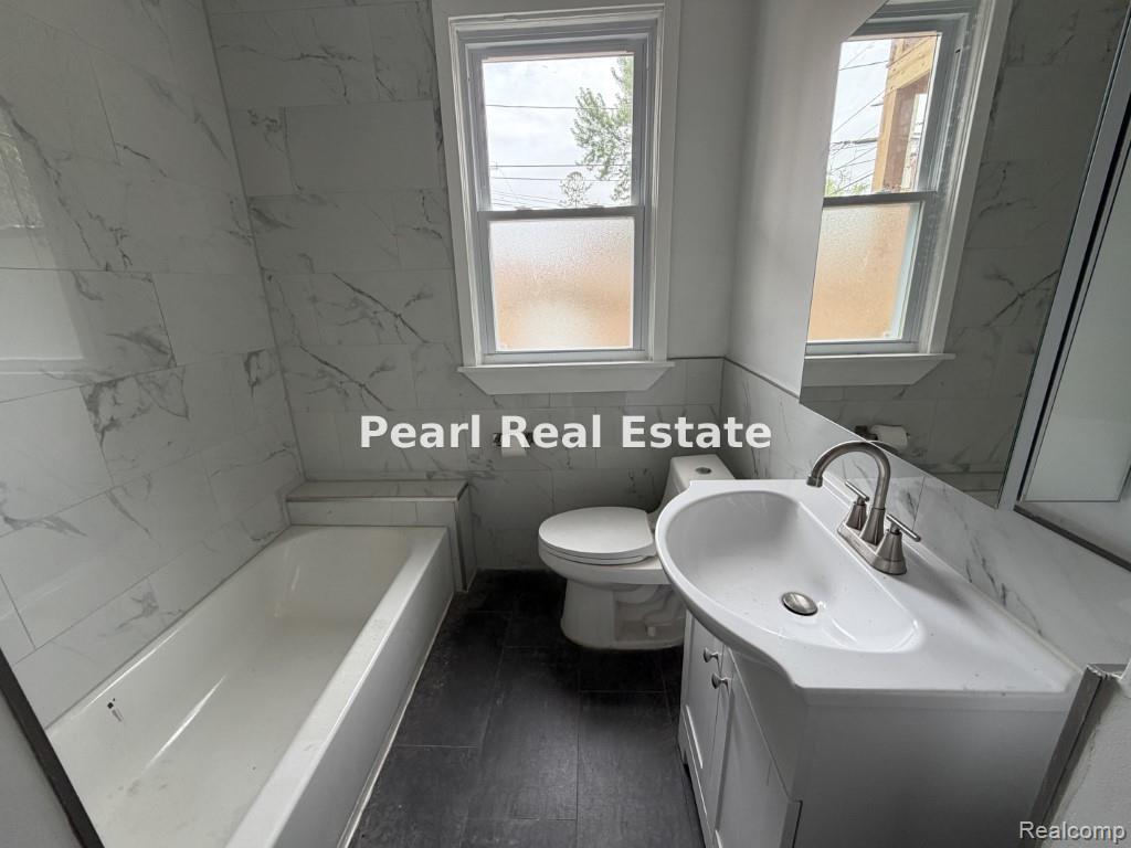 2s Santa Rosa Drive Detroit, MI 48221 - Photo 14 of 16 Bathroom featuring a white bathtub, a single vanity with storage, a toilet, and two windows