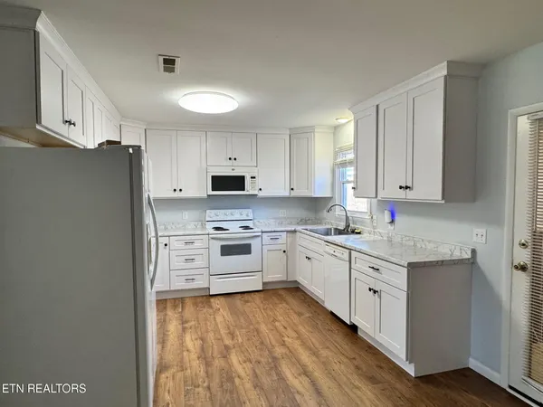 a kitchen with granite countertop a sink stove and refrigerator