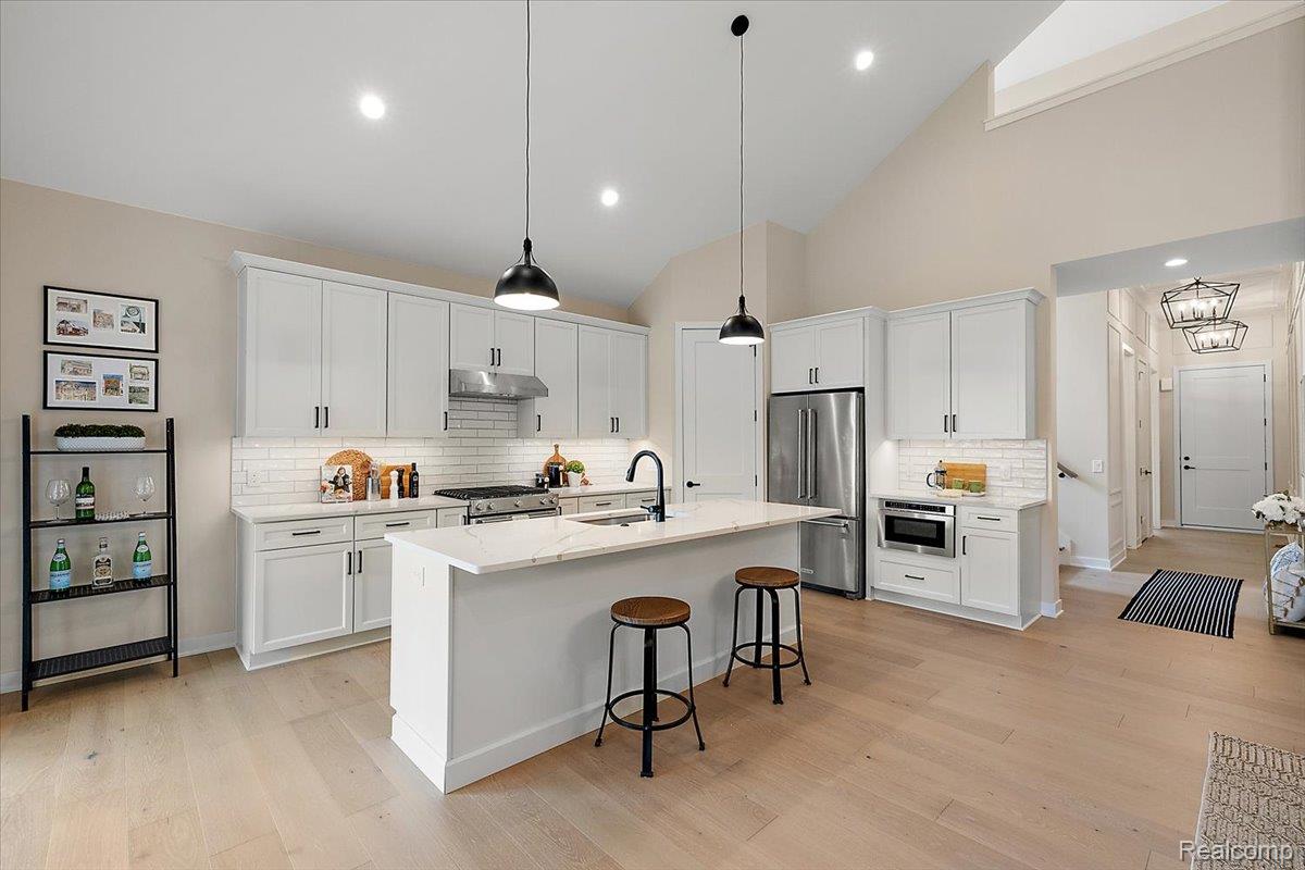 2032 Breckenridge Court, Unit 9 Rochester, MI 48309 - Photo 11 of 39 Kitchen featuring decorative backsplash, a breakfast bar, light wood-style floors, pendant lighting, and white cabinets