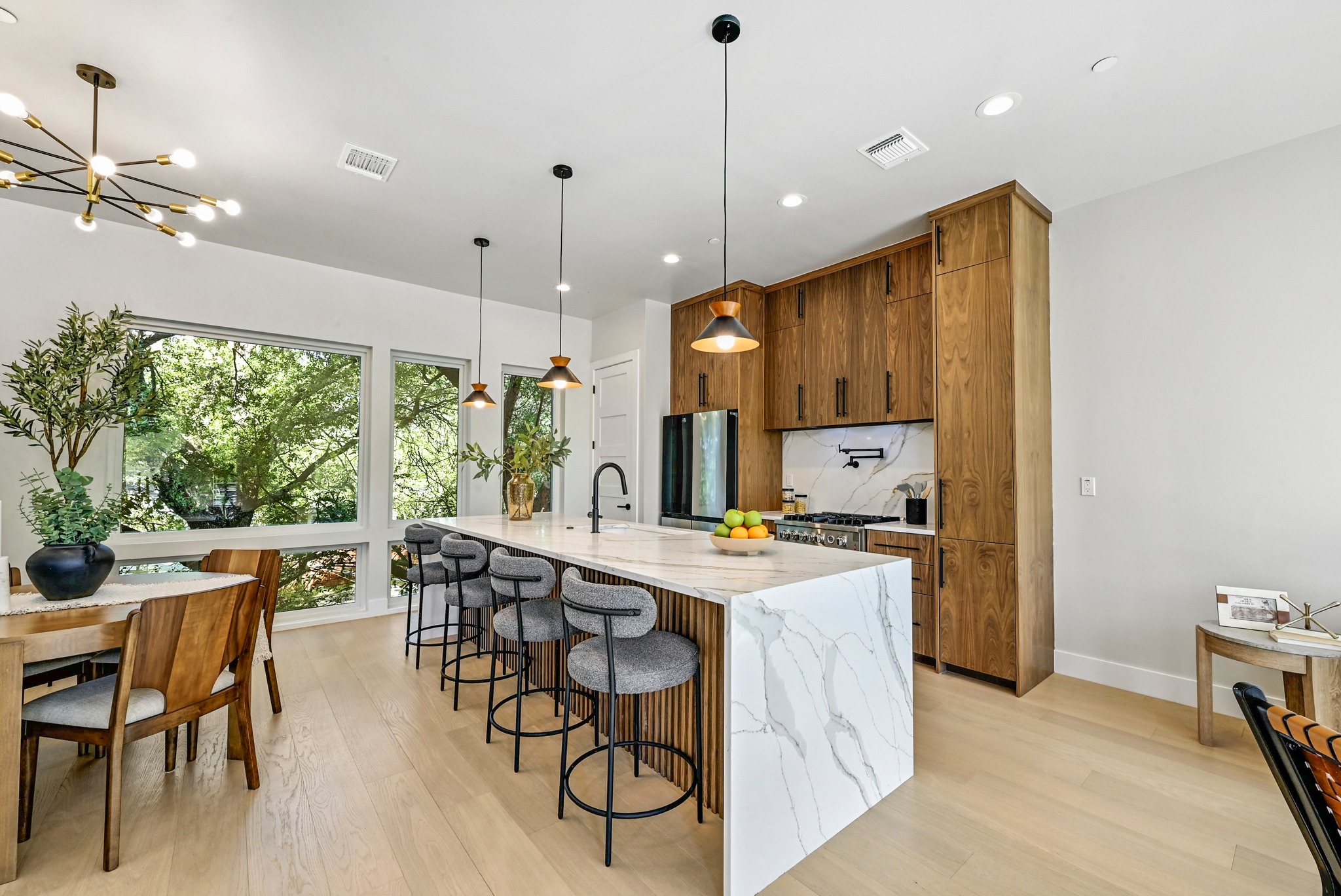 100 West Odell Street, Unit 3 Austin, TX 78752 - Photo 15 of 37 a kitchen with stainless steel appliances granite countertop a stove a refrigerator a kitchen island a dining table and chairs with wooden floor