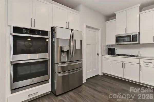 a kitchen with stainless steel appliances white cabinets white stove a microwave and a refrigerator