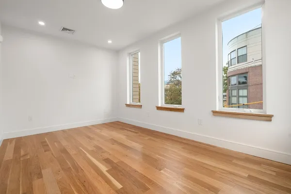 a view of an empty room with a window and wooden floor