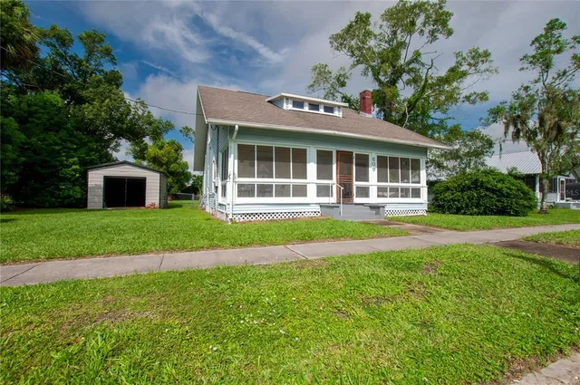 a front view of a house with a yard and potted plants