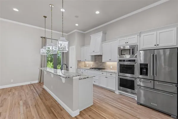 a kitchen with kitchen island white cabinets stainless steel appliances and wooden floor
