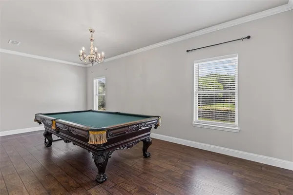 a room with wooden floors pool table and windows