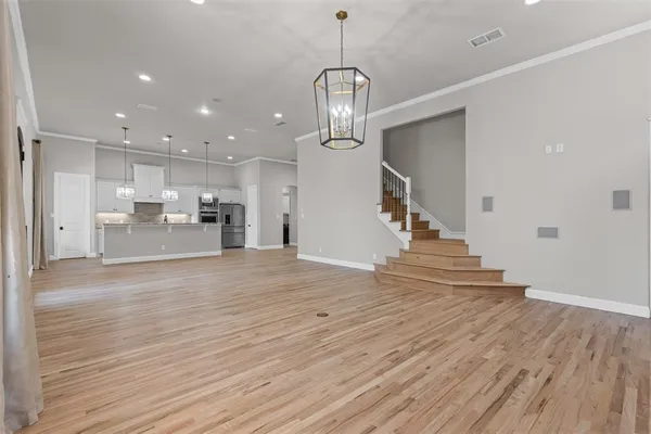 a view of a room with wooden floor staircase and a kitchen