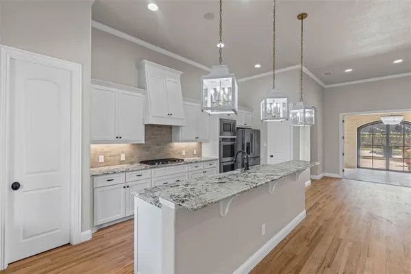 a large kitchen with stainless steel appliances kitchen island granite countertop a sink a counter space and wooden floor