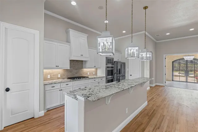 a large kitchen with stainless steel appliances kitchen island granite countertop a sink a counter space and wooden floor