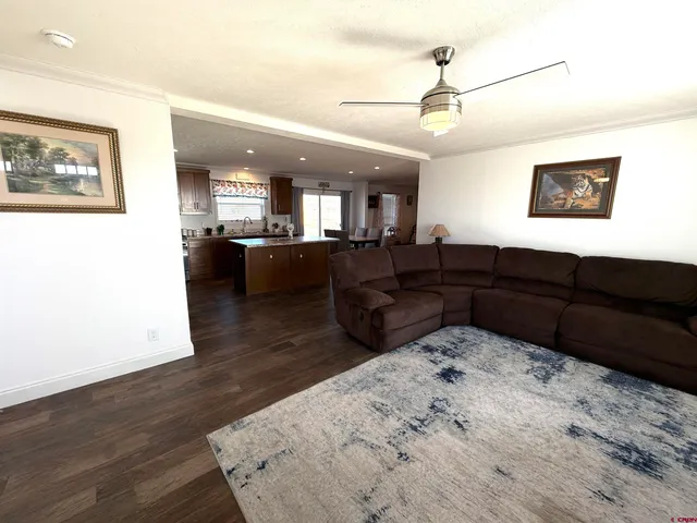 a living room with couches and kitchen view with wooden floor