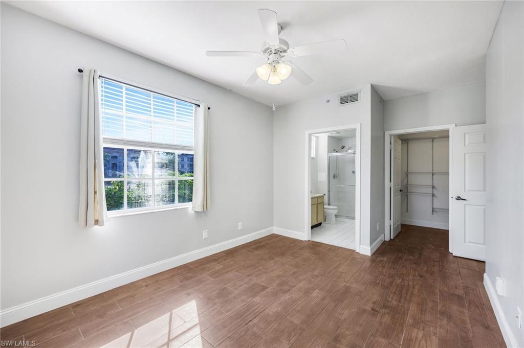 4620 St Croix Lane, Unit 911 Naples, FL 34109 - Photo 11 of 26 Primary bedroom featuring dark wood-type flooring, a spacious closet, and joining bathroom