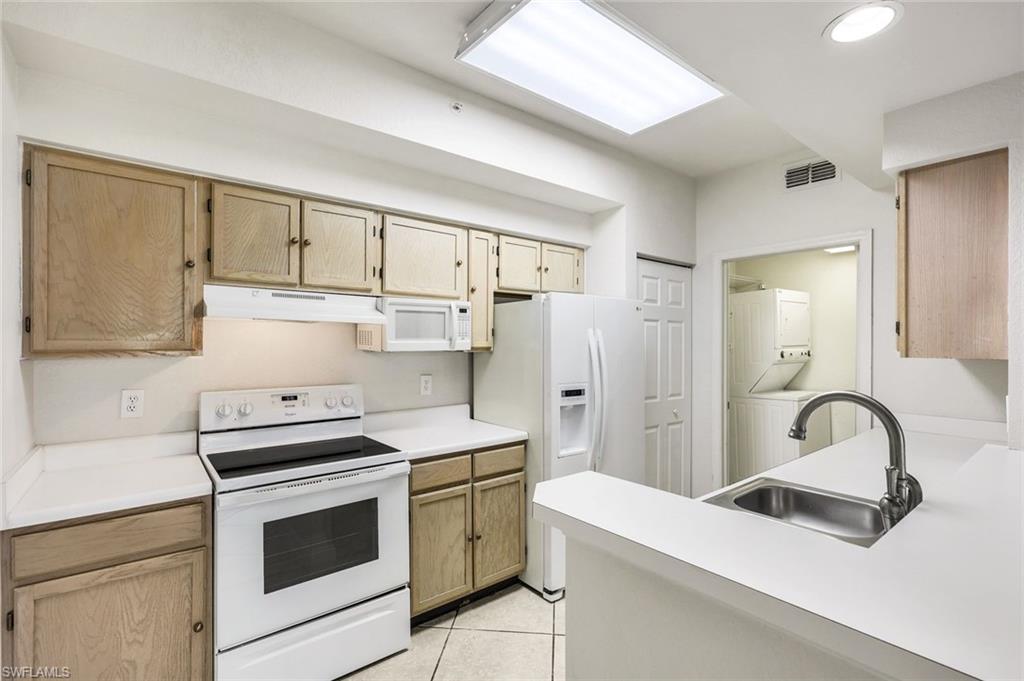 4620 St Croix Lane, Unit 911 Naples, FL 34109 - Photo 8 of 26 Kitchen with white appliances, light countertops and light brown cabinetry. Notice the Laundry Room in the background