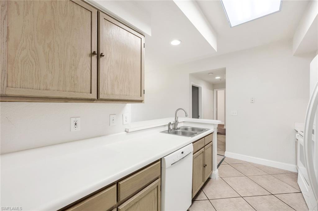 4620 St Croix Lane, Unit 911 Naples, FL 34109 - Photo 9 of 26 Kitchen featuring light countertops, light brown cabinetry, white appliances, and light tile patterned floors