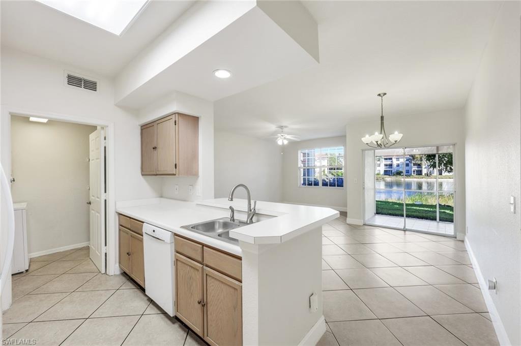 4620 St Croix Lane, Unit 911 Naples, FL 34109 - Photo 26 of 26 Kitchen with light brown cabinets, white countertops, open floor plan, light tile patterned flooring, and white appliances.