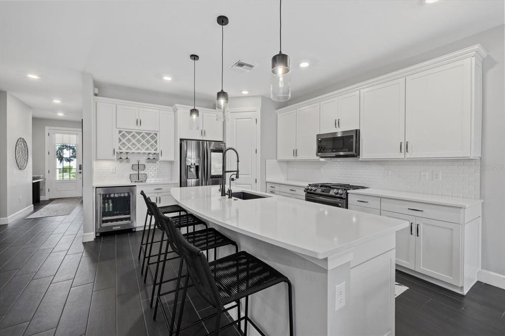 3508 Anchor Bay Trail Lakewood Ranch, FL 34211 - Photo 10 of 74 a kitchen with stainless steel appliances a stove a sink a refrigerator a center island a table and chairs