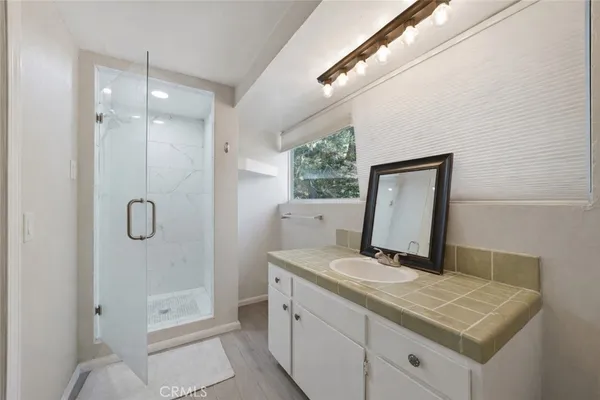 a bathroom with a granite countertop sink a mirror and shower