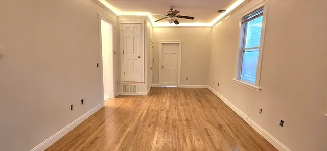a view of a hallway with wooden floor and a bathroom
