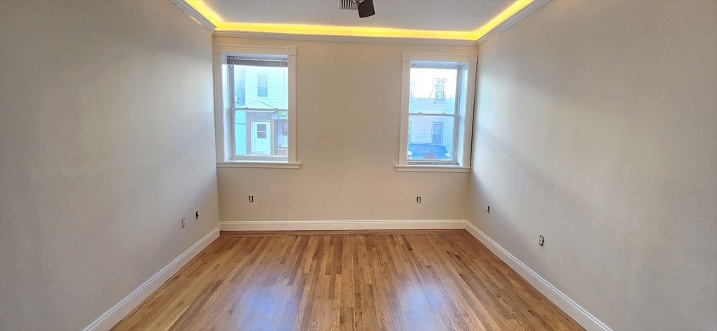 191 Maverick Street, Unit 1L Boston, MA 02128 - Photo 13 of 16 an empty room with wooden floor and windows