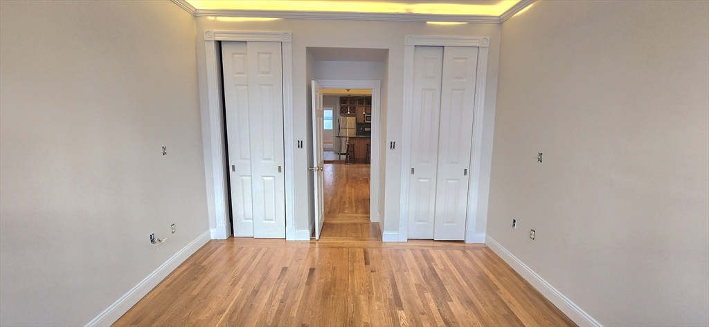 191 Maverick Street, Unit 1L Boston, MA 02128 - Photo 16 of 16 a view of an empty room with wooden floor and a window