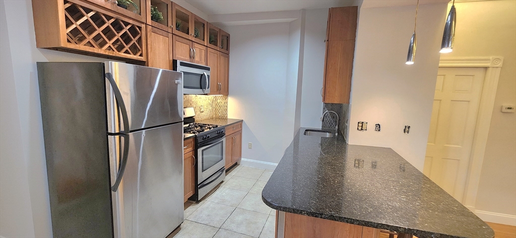 191 Maverick Street, Unit 1L Boston, MA 02128 - Photo 3 of 16 a kitchen with stainless steel appliances granite countertop a refrigerator and a sink