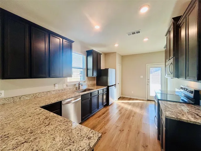 a kitchen with stainless steel appliances kitchen island granite countertop a sink stove and refrigerator