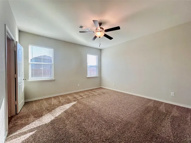 an empty room with windows and fan