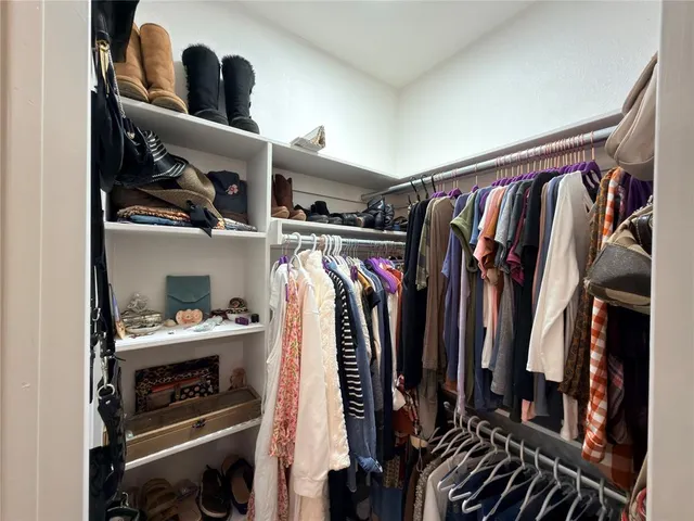 a view of walk in closet with clothes and shoes