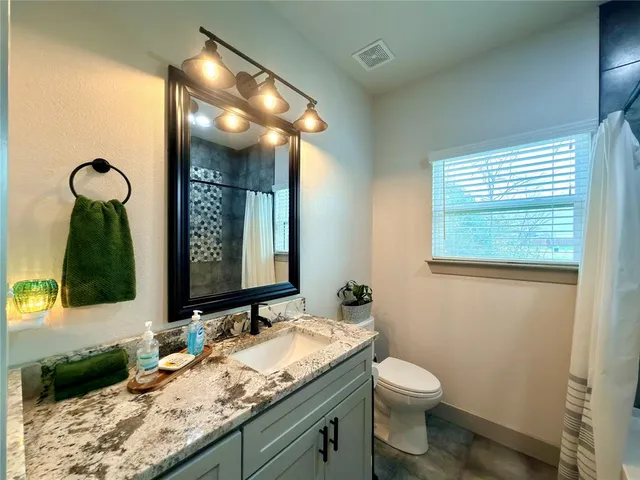 a bathroom with a granite countertop sink toilet and mirror