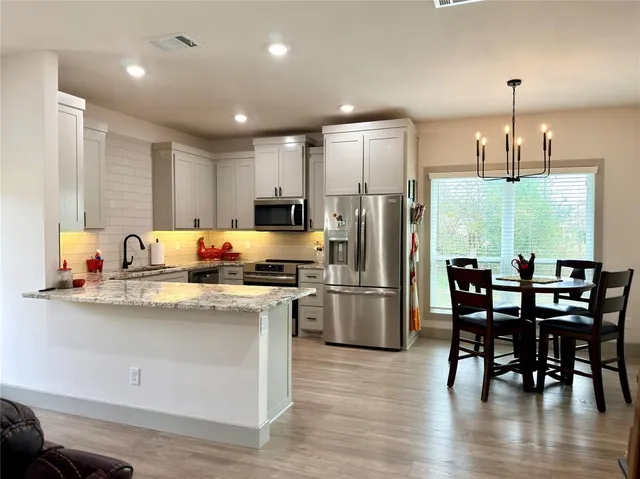 a kitchen with stainless steel appliances granite countertop a sink a stove a refrigerator cabinets and dining table