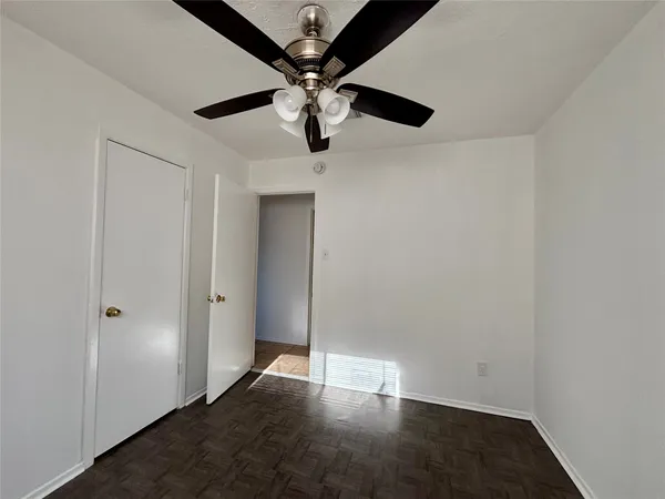 an empty room with wooden floor closet and ceiling fan