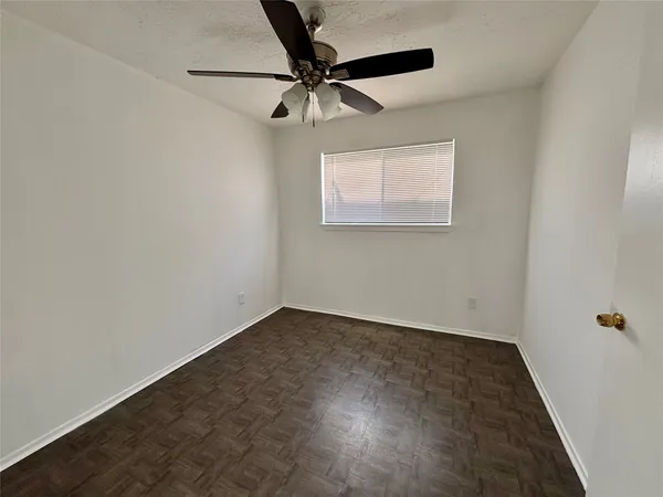an empty room with a ceiling fan and wooden floor