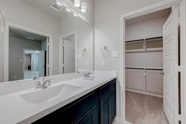 a bathroom with a double vanity sink mirror and refrigerator