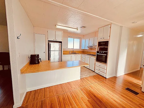 a large white kitchen with wooden floors and stainless steel appliances