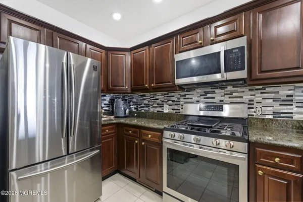 a kitchen with stainless steel appliances granite countertop a stove microwave and refrigerator