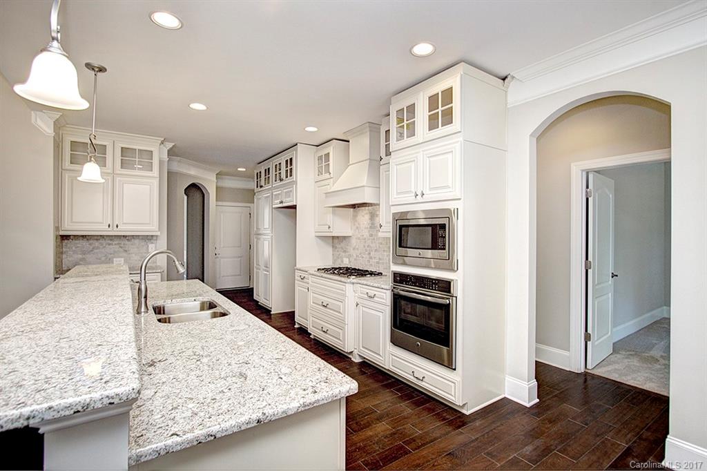 4933 River Oaks Road, Unit 113 Clover, SC 29710 - Photo 5 of 24 a kitchen with stainless steel appliances granite countertop a stove top oven a sink a refrigerator and white cabinets with wooden floor