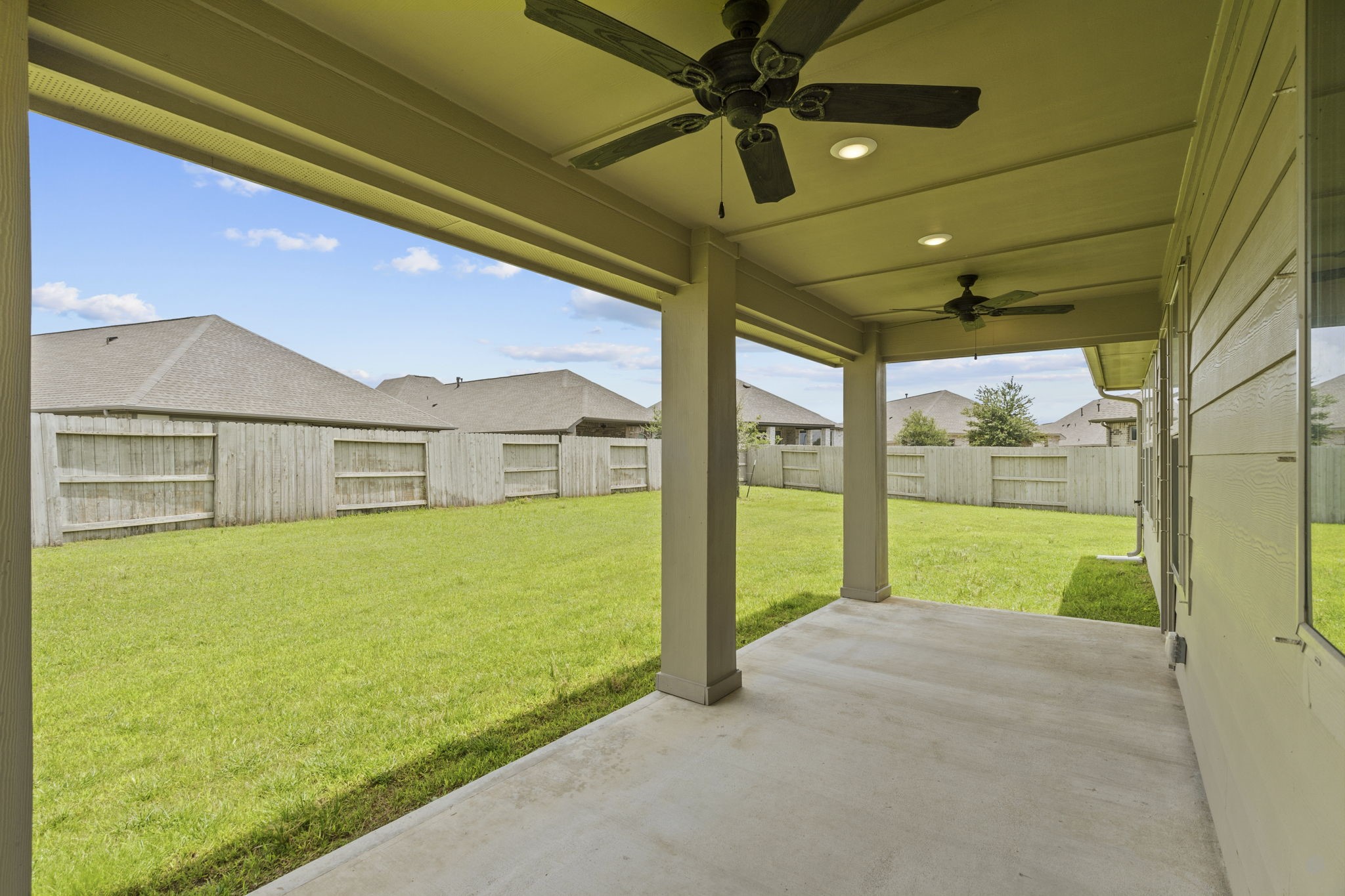 2011 Oak Leaf Court Manvel, TX 77578 - Photo 22 of 28 Large covered patio with ceiling fans, overlooking a spacious backyard. The area is bordered by a wooden fence, offering privacy and a great outdoor space for relaxation or entertaining.