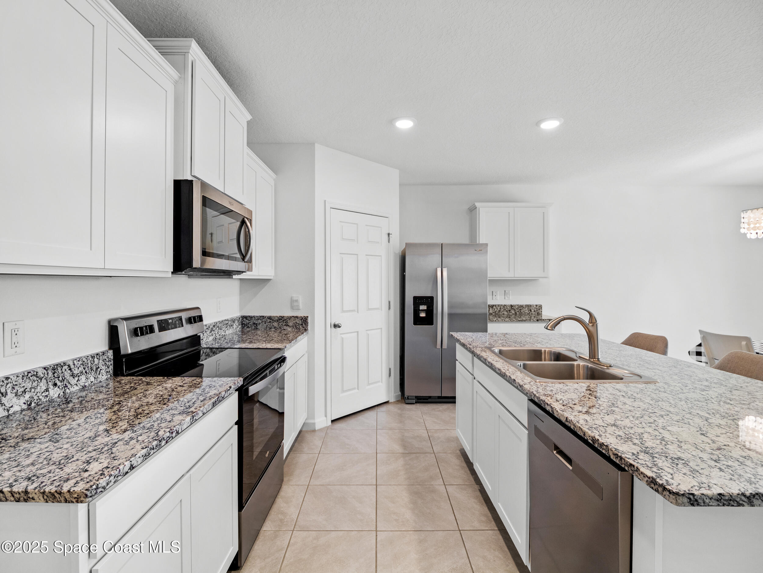 5678 Waterfall Place Grant, FL 32949 - Photo 10 of 25 a kitchen with granite countertop kitchen island stainless steel appliances a sink stove top oven and refrigerator
