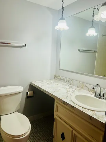 a bathroom with a granite countertop sink toilet and a mirror