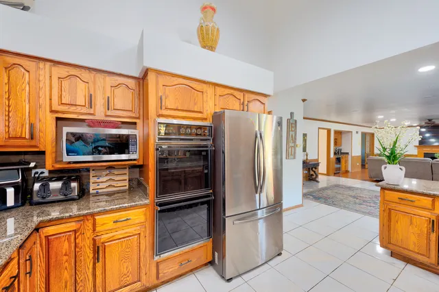 a kitchen with stainless steel appliances granite countertop a refrigerator a stove and a sink with granite countertops