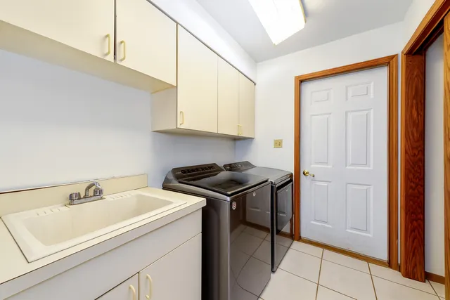 a view of a utility room with sink cabinet and a window