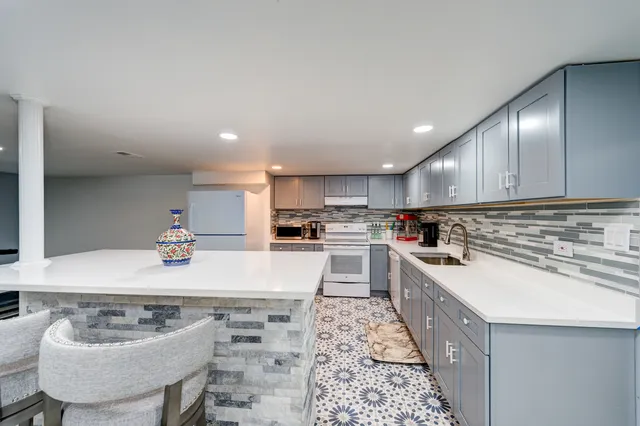 a kitchen with stainless steel appliances a sink a stove a refrigerator and white cabinets with wooden floor