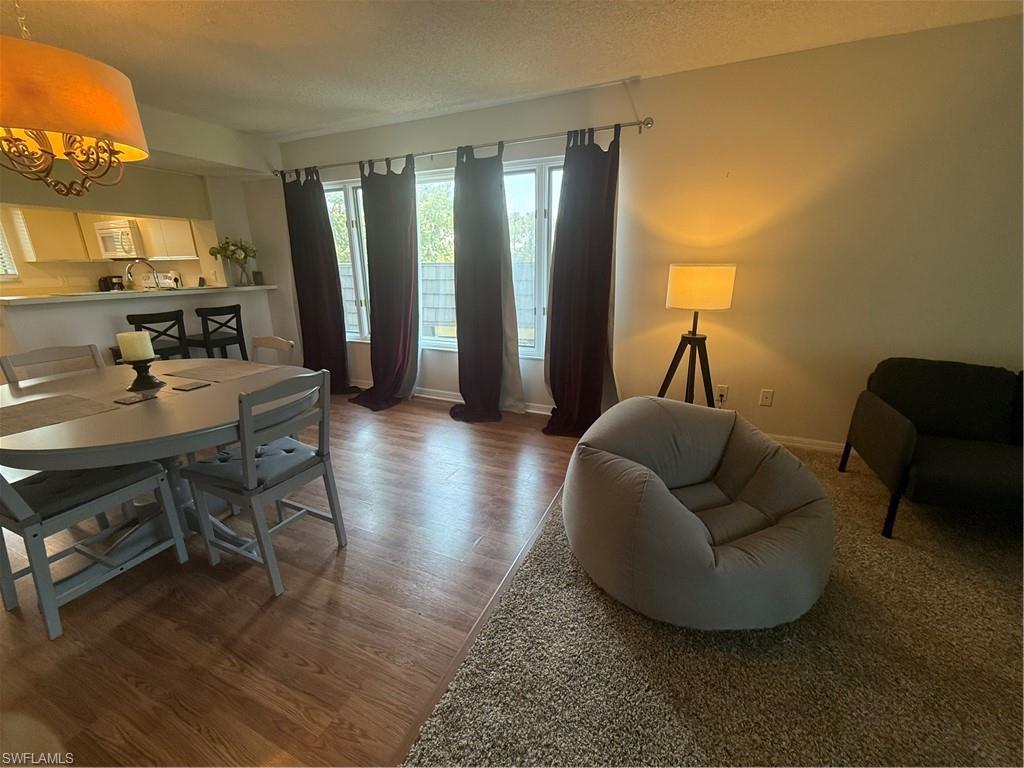 1645 Spoonbill Lane, Unit C Naples, FL 34105 - Photo 4 of 50 Dining space featuring light wood-style floors, plenty of natural light, a textured ceiling, and a chandelier
