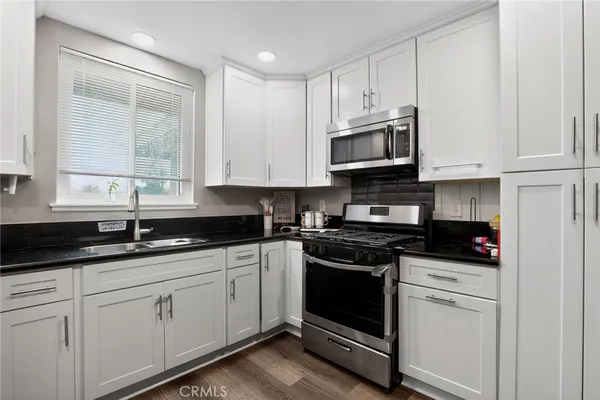 a kitchen with granite countertop white cabinets and white appliances
